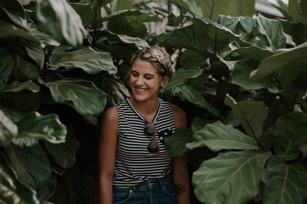 Woman with braided hair laughs in greenhouse Woman with braided hair laughs in greenhouse