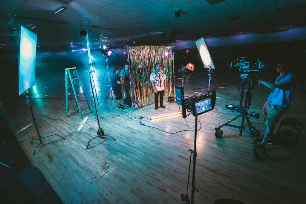 music video set with neon lighting and an artist posing in front of gold foil