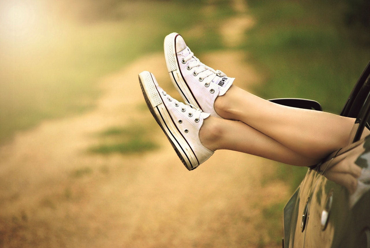 woman wearing converse hanging her legs outside of a car window